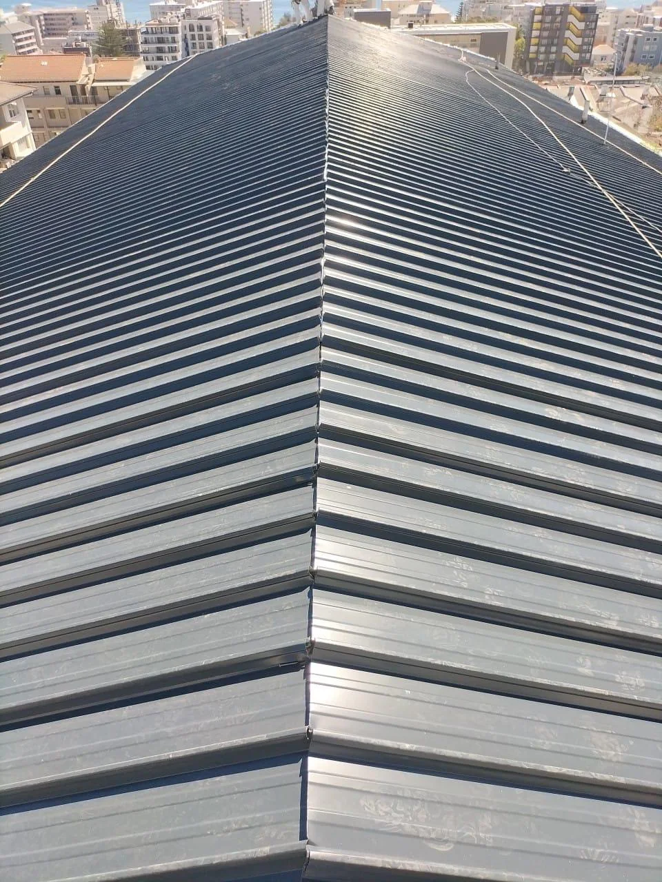 Completed dark pitched roofing on an urban building