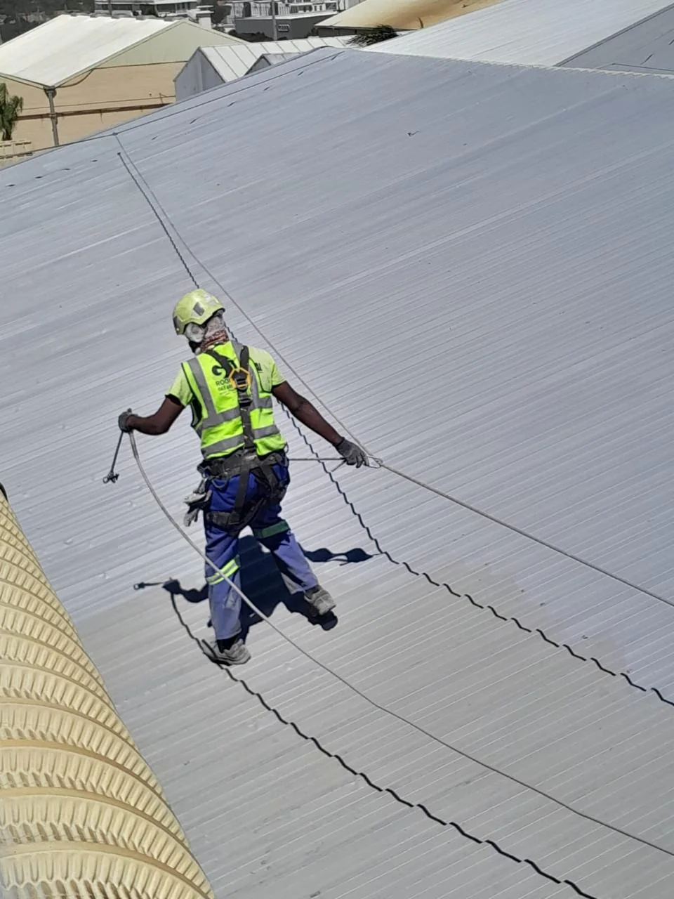 Worker with safety harness on a metal roof